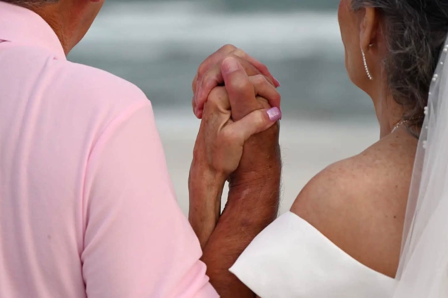 Couple holding hands beach wedding