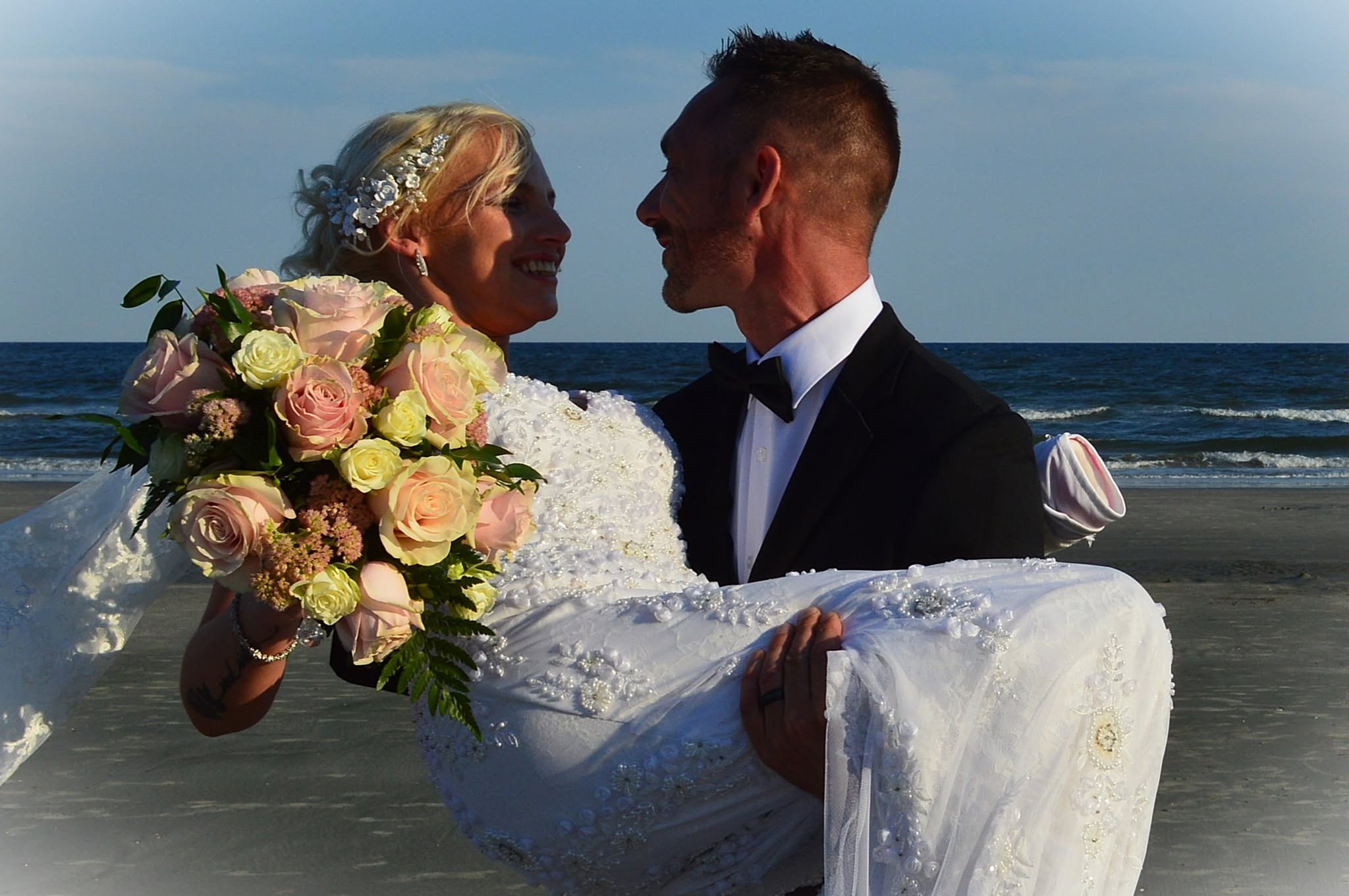 Groom carrying bride in ocean waves